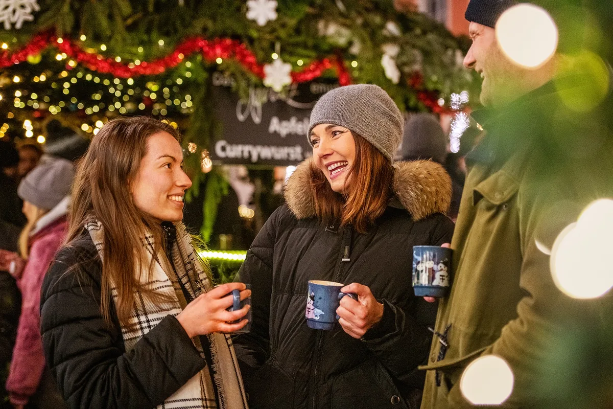 G&auml;ste auf dem festlich beleuchteten Weihnachtsmarkt am See