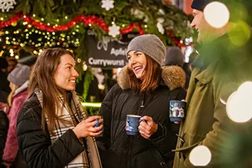 Besucherinnen mit hei&szlig;en Getr&auml;nken auf dem Weihnachtsmarkt