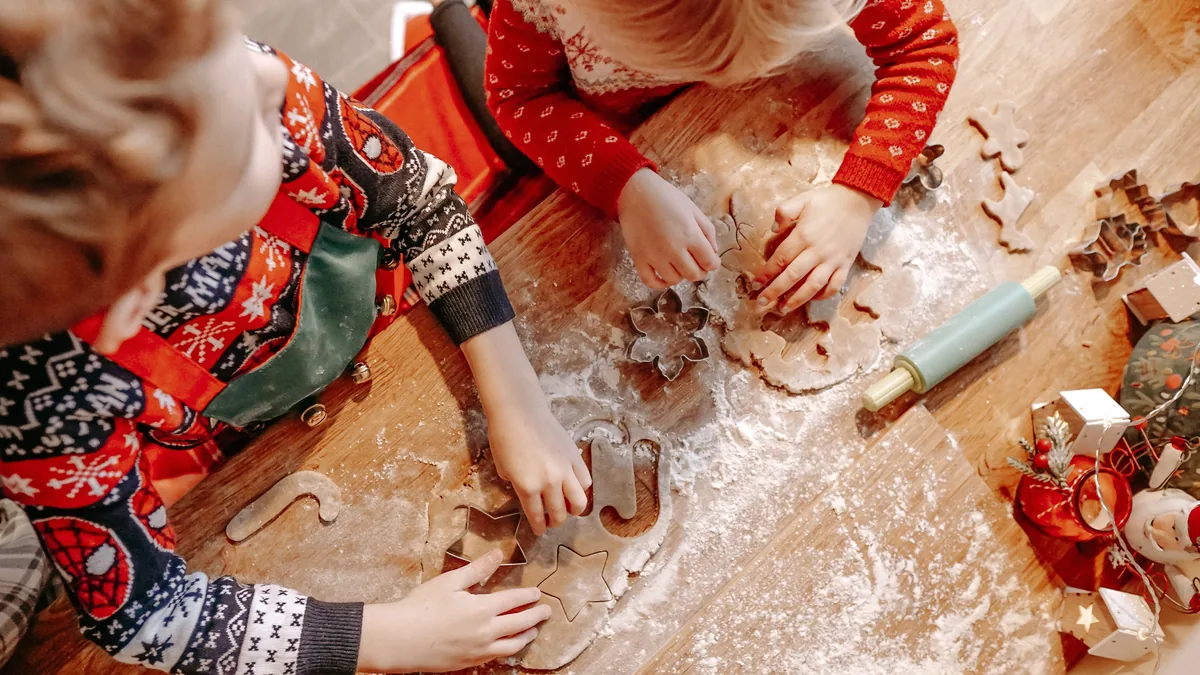 Kinder stechen gemeinsam Weihnachtspl&auml;tzchen aus
